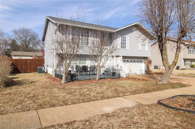 raised ranch featuring a garage, a front yard, and central AC unit