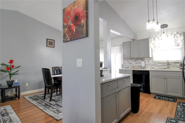 kitchen with pendant lighting, lofted ceiling, black dishwasher, and gray cabinetry