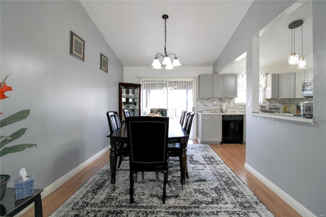 dining room with lofted ceiling, light hardwood / wood-style flooring, and a notable chandelier