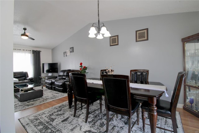 dining area with ceiling fan with notable chandelier, lofted ceiling, and hardwood / wood-style floors