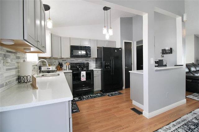 kitchen with gray cabinetry, sink, black appliances, and hanging light fixtures