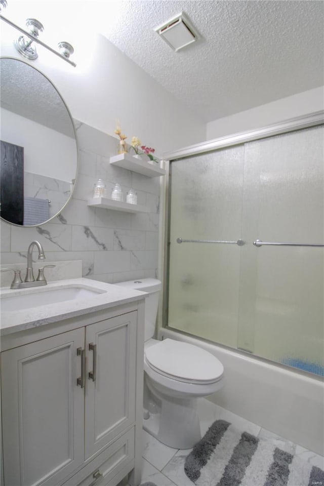 full bathroom with toilet, vanity, shower / bath combination with glass door, and a textured ceiling