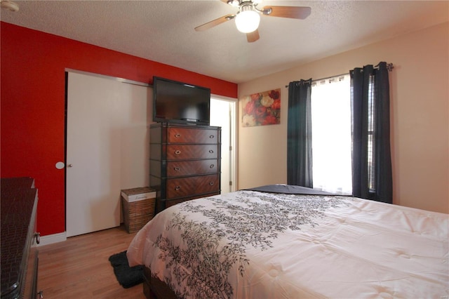 bedroom featuring ceiling fan, light hardwood / wood-style floors, a closet, and a textured ceiling