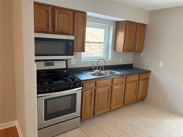 kitchen featuring light tile patterned flooring, appliances with stainless steel finishes, sink, and tile walls