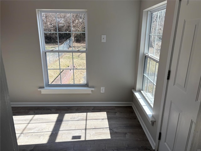 unfurnished dining area featuring dark wood-type flooring and plenty of natural light