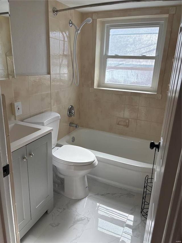 full bathroom with vanity, toilet, tiled shower / bath combo, and tile walls