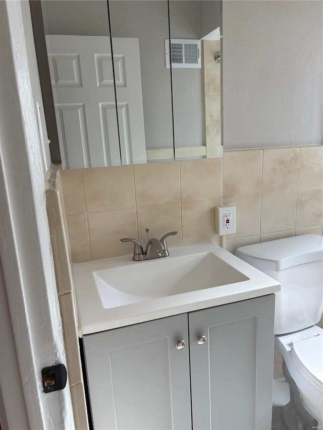 bathroom with vanity, tile walls, and toilet