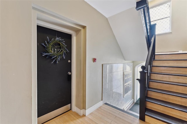 stairway with vaulted ceiling, baseboards, and wood finished floors