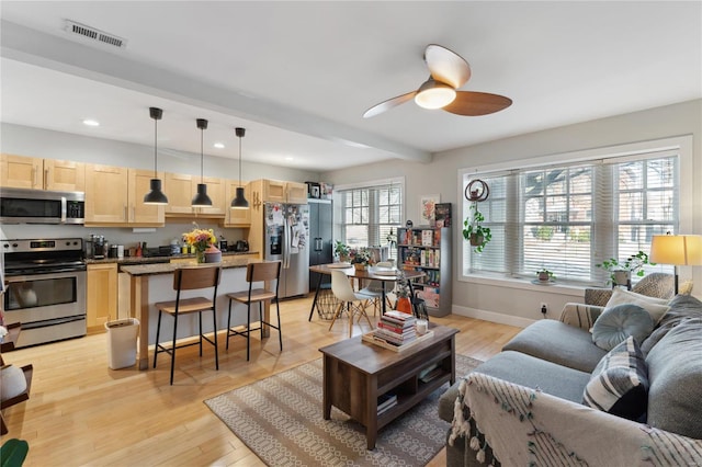 living area featuring light wood finished floors, visible vents, baseboards, beamed ceiling, and recessed lighting