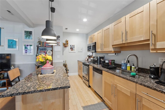 kitchen featuring visible vents, stainless steel appliances, light brown cabinetry, and a sink