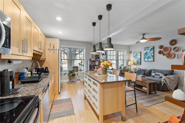 kitchen featuring a breakfast bar area, stainless steel appliances, light wood-style floors, open floor plan, and a center island