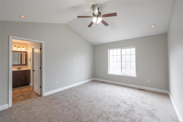 unfurnished bedroom featuring sink, ceiling fan, connected bathroom, light carpet, and vaulted ceiling