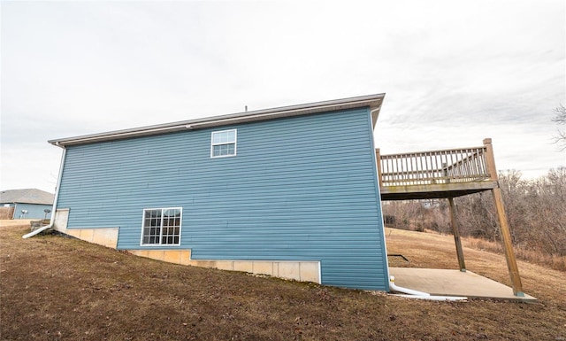 view of property exterior featuring a wooden deck and a lawn