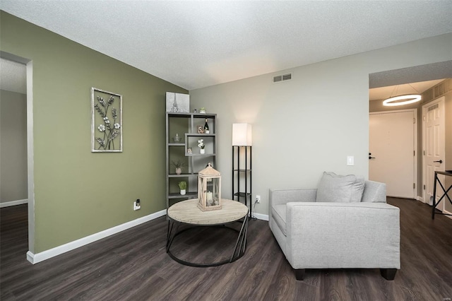 sitting room with lofted ceiling, dark hardwood / wood-style floors, and a textured ceiling