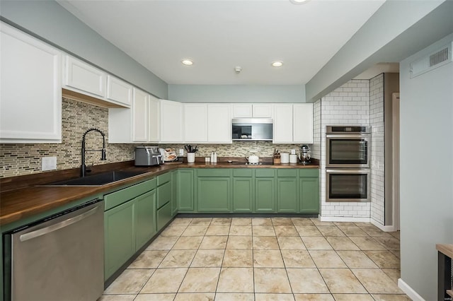 kitchen with sink, appliances with stainless steel finishes, backsplash, white cabinets, and wood counters