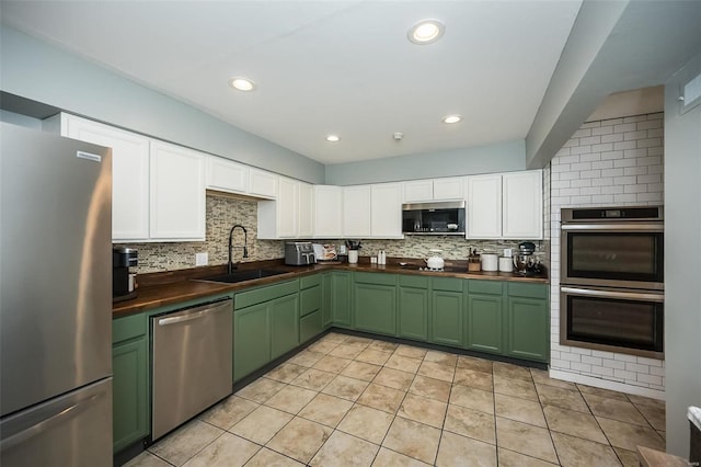 kitchen with butcher block countertops, sink, backsplash, and appliances with stainless steel finishes