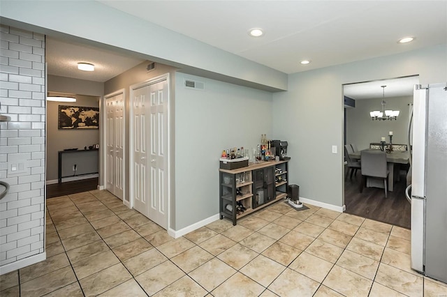 hall featuring light tile patterned flooring and an inviting chandelier