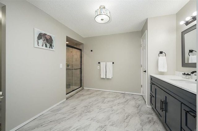 bathroom featuring vanity, a shower with shower door, and a textured ceiling