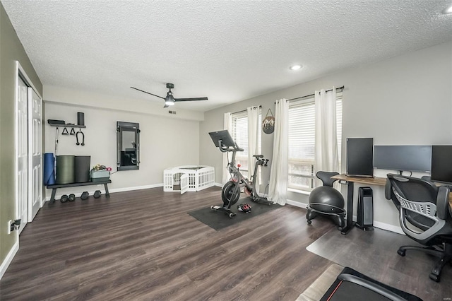 workout room with ceiling fan, dark hardwood / wood-style floors, and a textured ceiling