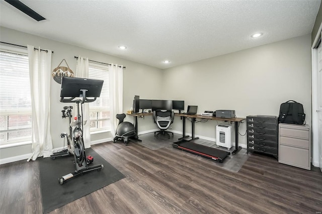 exercise area featuring dark wood-type flooring and a textured ceiling