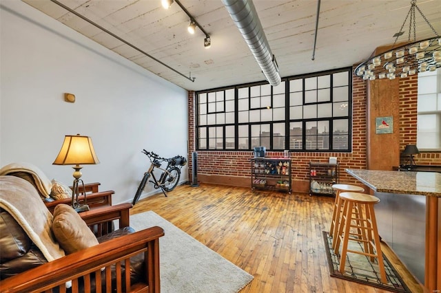 living room featuring a healthy amount of sunlight, track lighting, brick wall, and light hardwood / wood-style floors