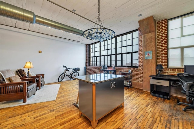 office space with brick wall and light hardwood / wood-style flooring