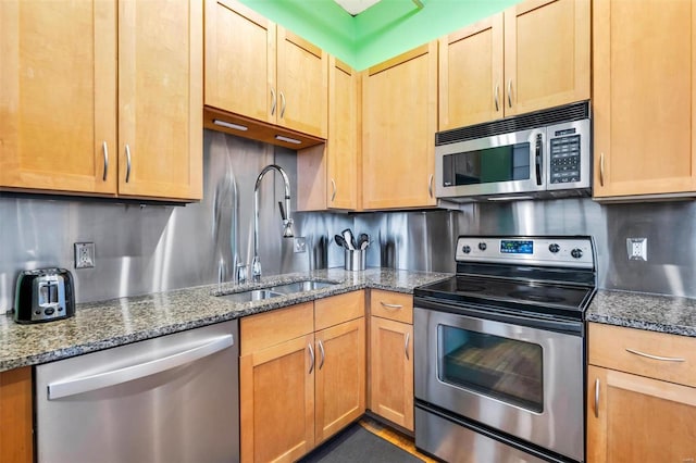 kitchen with tasteful backsplash, appliances with stainless steel finishes, sink, and dark stone countertops