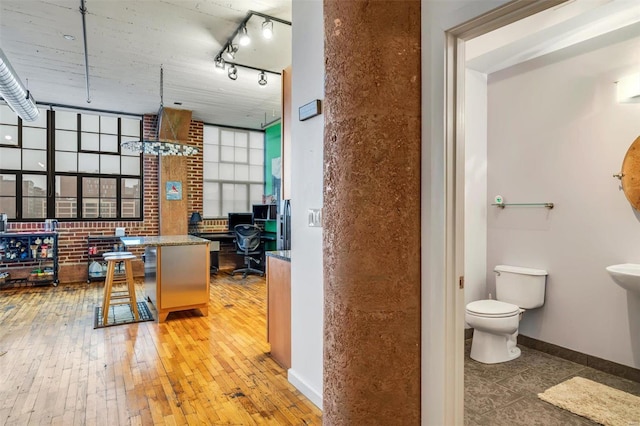 interior space featuring wood-type flooring, brick wall, and track lighting