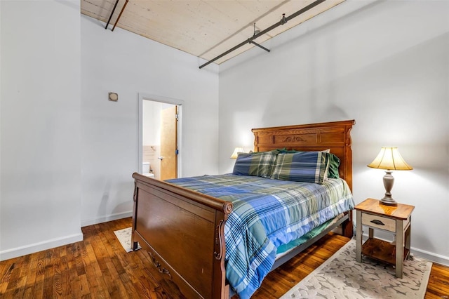 bedroom featuring ensuite bath and dark wood-type flooring