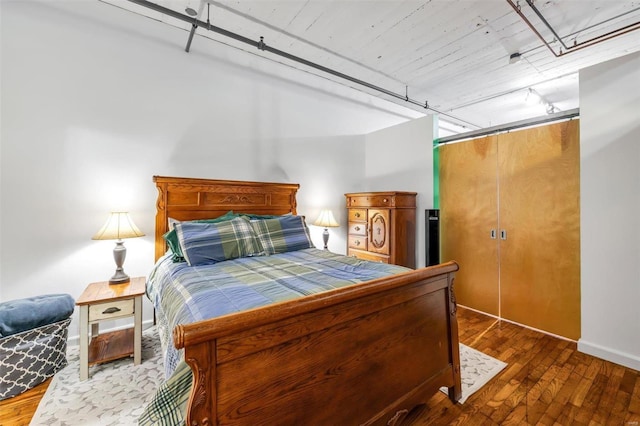 bedroom with track lighting and hardwood / wood-style floors