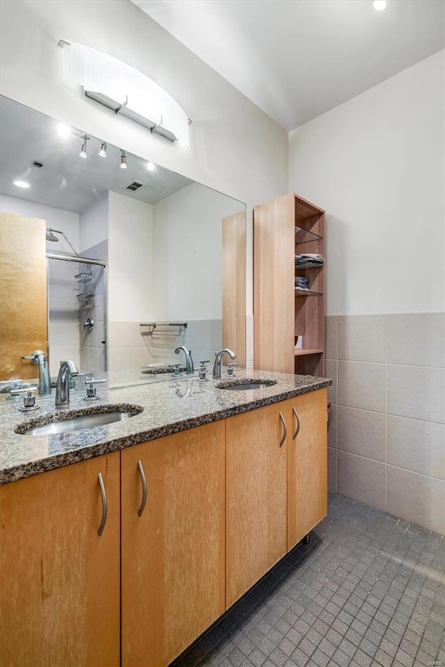 bathroom featuring walk in shower, vanity, and tile walls