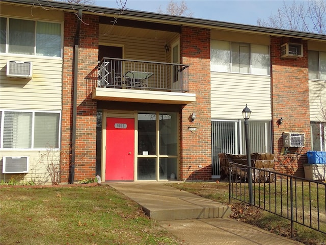 rear view of property with a wall unit AC and a balcony