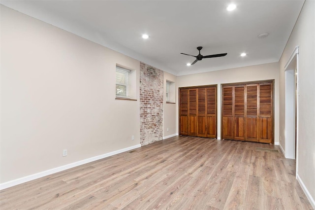 unfurnished bedroom featuring multiple closets, ceiling fan, and light wood-type flooring