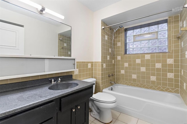 full bathroom with tiled shower / bath, tile walls, vanity, toilet, and tile patterned floors