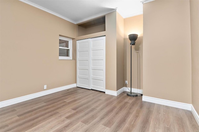 unfurnished bedroom with crown molding, a closet, and light wood-type flooring