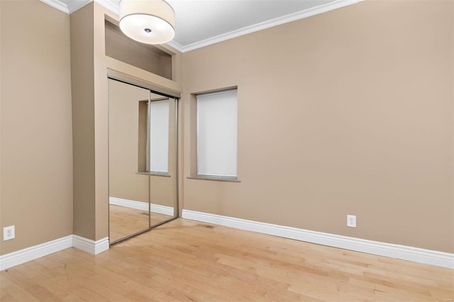 unfurnished bedroom featuring hardwood / wood-style flooring, crown molding, and a closet