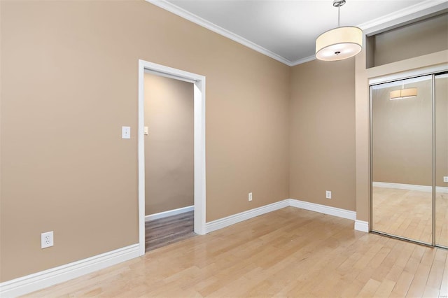 unfurnished bedroom with crown molding, light hardwood / wood-style floors, and a closet