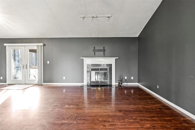 unfurnished living room with french doors, wood finished floors, a high end fireplace, and baseboards