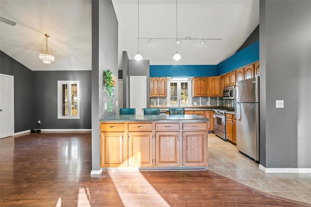 kitchen featuring light wood finished floors, tasteful backsplash, appliances with stainless steel finishes, and pendant lighting