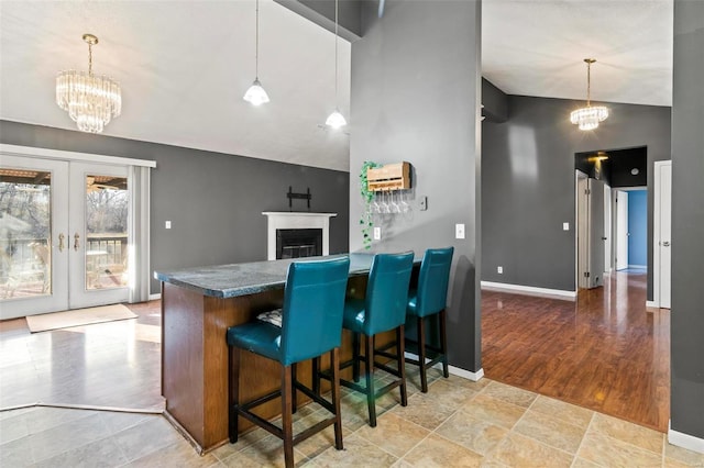 kitchen featuring a breakfast bar area, an inviting chandelier, french doors, dark countertops, and pendant lighting