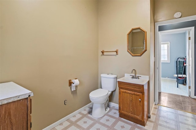 bathroom featuring baseboards, vanity, toilet, and tile patterned floors