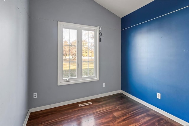 unfurnished room with lofted ceiling, plenty of natural light, dark wood finished floors, and visible vents