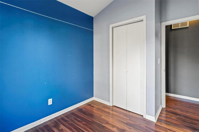 unfurnished bedroom with dark wood-style floors, a closet, visible vents, and baseboards