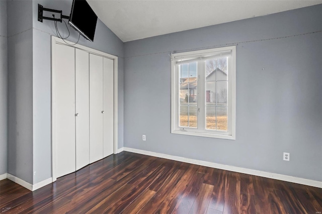 unfurnished bedroom featuring a closet, baseboards, and dark wood-type flooring