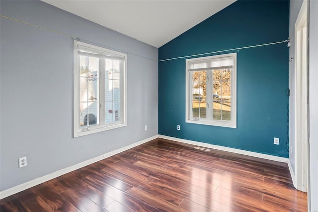 empty room with dark wood-type flooring, lofted ceiling, plenty of natural light, and baseboards