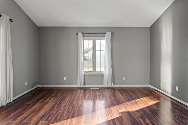 unfurnished room with dark wood-style floors, visible vents, and baseboards