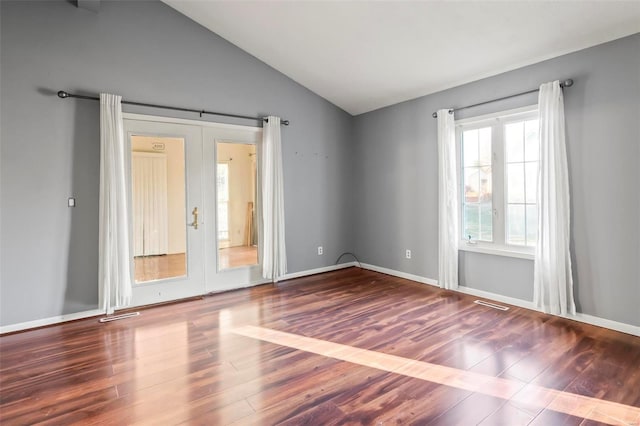 empty room featuring lofted ceiling, french doors, visible vents, and wood finished floors