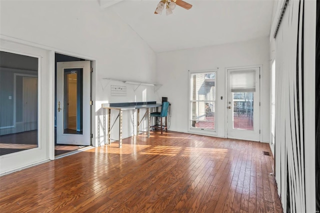 unfurnished living room with high vaulted ceiling, wood-type flooring, visible vents, and a ceiling fan