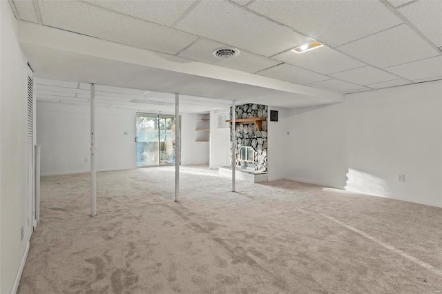 basement with a drop ceiling, visible vents, and light colored carpet