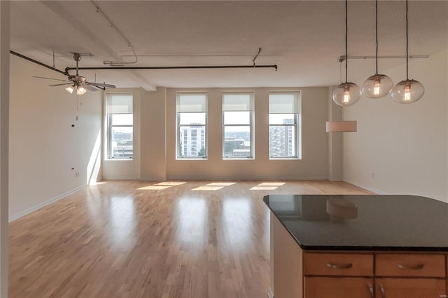 kitchen featuring pendant lighting, rail lighting, ceiling fan, and light wood-type flooring